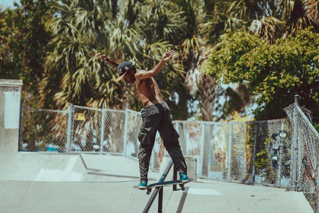 man in black tank top and black pants doing skateboard stunts