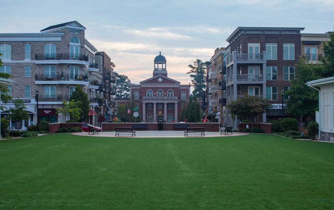 a grassy area with benches and a clock tower in the background